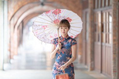 20 'li yaşlarda Tayvanlı genç bir kadın, mavi bir keongsam giyiyor. Elinde Çin desenli bir şemsiyeyle Wanhua, Taipei, Tayvan' da bir kültür bölgesinde geziniyor.
