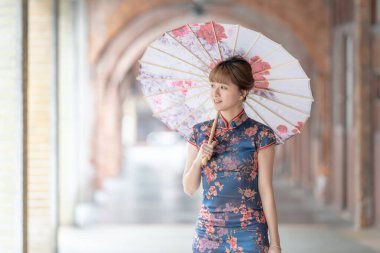 20 'li yaşlarda Tayvanlı genç bir kadın, mavi bir keongsam giyiyor. Elinde Çin desenli bir şemsiyeyle Wanhua, Taipei, Tayvan' da bir kültür bölgesinde geziniyor.