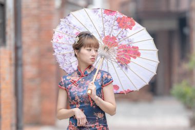 20 'li yaşlarda Tayvanlı genç bir kadın, mavi bir keongsam giyiyor. Elinde Çin desenli bir şemsiyeyle Wanhua, Taipei, Tayvan' da bir kültür bölgesinde geziniyor.