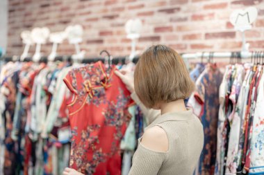 Tayvan 'ın Tayvan bölgesindeki Wanhua semtindeki kiralık bir dükkandan giyecek keongsam arayan 20' li yaşlarda, krem rengi kıyafetler giyen genç bir Tayvanlı kadın.