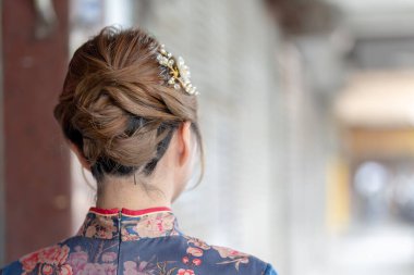 20 'li yaşlardaki Tayvanlı genç bir kadın mavi bir keongsam giyiyor ve kırmızı bir çanta taşıyor. Wanhua Bölgesi, Tayvan sokaklarında geziniyor.