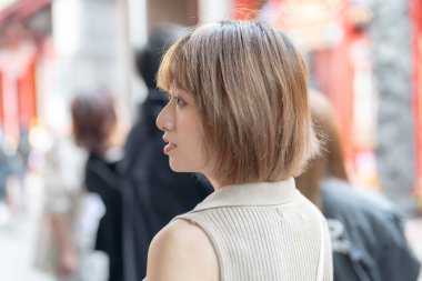 Tayvan 'ın Tayvan bölgesindeki Wanhua semtindeki ünlü Longshan Tapınağı' nda gezen 20 'li yaşlarda krem rengi kıyafetler giyen genç bir Tayvanlı kadın.