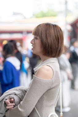 Young Taiwanese woman in her 20s wearing cream-colored clothes, strolling through the famous tourist attraction Longshan Temple in Wanhua District, Taipei, Taiwan clipart