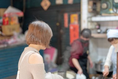 Tayvan 'ın Tayvan bölgesindeki Wanhua semtindeki ünlü Longshan Tapınağı' nda gezen 20 'li yaşlarda krem rengi kıyafetler giyen genç bir Tayvanlı kadın.