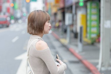 20 'li yaşlarda, Tayvan, Tayvan' da Wanhua Bölgesi sokaklarında gezen krem renkli kıyafetler giyen genç bir Tayvanlı kadın.