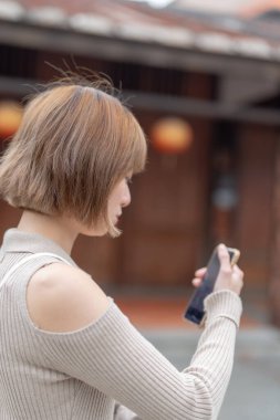 20 'li yaşlarda, Tayvan, Tayvan' da Wanhua Bölgesi sokaklarında gezen krem renkli kıyafetler giyen genç bir Tayvanlı kadın.