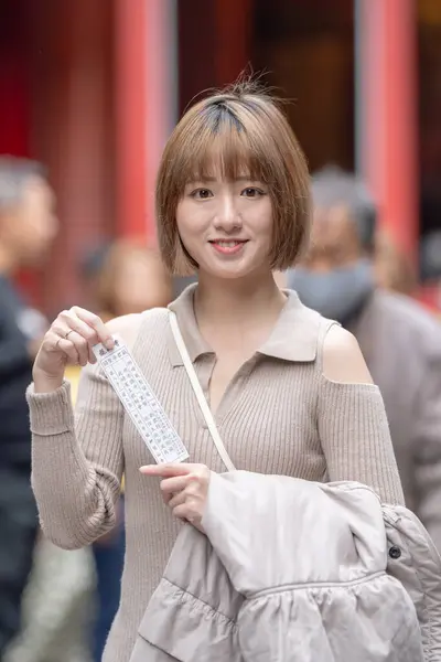 stock image Young Taiwanese woman in her 20s wearing cream-colored clothes, drawing a fortune slip (omikuji) at the famous tourist attraction Longshan Temple in Wanhua District, Taipei, Taiwan