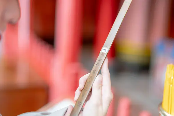 stock image Young Taiwanese woman in her 20s wearing cream-colored clothes, drawing a fortune slip (omikuji) at the famous tourist attraction Longshan Temple in Wanhua District, Taipei, Taiwan