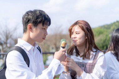 20 'li yaşlarda genç Tayvanlı bir çift, üniversite öğrencileri, Maokong, Wenshan Bölgesi, Taipei, Tayvan' da bir kafede satılan yumuşak servis dondurmalarını mutlulukla paylaşıyorlar.