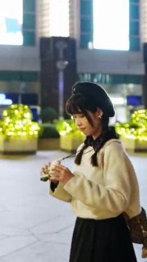 Tayvan 'ın Taipei bölgesinin Xinyi semtindeki lüks bir alışveriş merkezinde 20' li yaşlarda genç ve tatlı bir kadının gece vakti gezintisi ve yürüyüşünün dikey videosu.