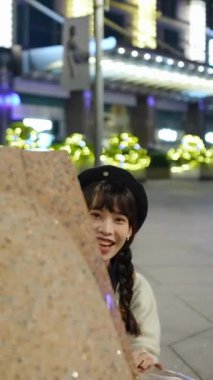 Taipei, Xinyi Bölgesi 'nin lüks bir alışveriş merkezinde 20' li yaşlarda genç ve tatlı bir Tayvanlı kadının gece vakti oturup aydınlanmasının dikey yavaş çekim videosu.