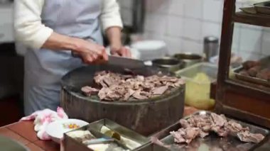 Tayvanlı bir kadın, Tayvan 'ın Wanhua semtindeki bir alışveriş sokağındaki yerel bir restoranın mutfağında etlerin malzemelerini kesiyor..
