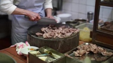 Tayvanlı bir kadın, Tayvan 'ın Wanhua semtindeki bir alışveriş sokağındaki yerel bir restoranın mutfağında etlerin malzemelerini kesiyor..