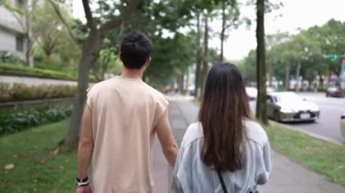 Tayvanlı genç bir çift yirmili yaşlarda ilkbaharda öğlen vakti Xinyi Bölgesi sokaklarında yürüyor. Adam kolsuz bir bluz giyiyor ve kadın kot ceket giyiyor..