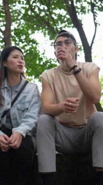 Tayvanlı genç bir çiftin Taipei 'deki Xinyi Bölgesi dağlarında oturup konuştuğu dikey bir video. Adam kolsuz bir bluz giyiyor ve kadın kot ceket giyiyor..