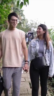 Tayvanlı genç bir çiftin Taipei 'nin Xinyi İlçesi' ndeki küçük bir patikada yürüdüğü ve konuştuğu dikey bir video. Adam kolsuz bir bluz giyiyor ve kadın kot ceket giyiyor..