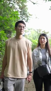 Tayvanlı genç bir çiftin Taipei 'nin Xinyi İlçesi' ndeki küçük bir patikada yürüdüğü ve konuştuğu dikey bir video. Adam kolsuz bir bluz giyiyor ve kadın kot ceket giyiyor..