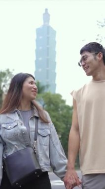 Tayvanlı genç bir çiftin yirmili yaşlarda Taipei 101 ile yan yana durduğu dikey bir video. Taipei şehrinin Xinyi ilçesinde bir bahar öğleden sonrası..