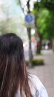 Tayvanlı genç bir çiftin yirmili yaşlarda Taipei 'nin Xinyi İlçesi sokaklarında yürürken çekilmiş dikey bir videosu. Adam kapüşonlu giyiyor.