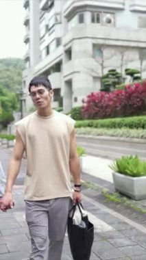 Tayvanlı genç bir çiftin yirmili yaşlarda Taipei 'nin Xinyi İlçesi sokaklarında yürürken çekilmiş dikey bir videosu. Adam kolsuz bir bluz giyiyor ve kadın kot ceket giyiyor..