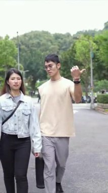 Tayvanlı genç bir çiftin yirmili yaşlarda Taipei 'nin Xinyi İlçesi sokaklarında yürürken çekilmiş dikey bir videosu. Adam kolsuz bir bluz giyiyor ve kadın kot ceket giyiyor..