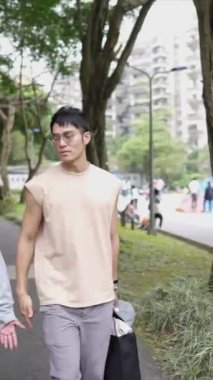 Tayvanlı genç bir çiftin yirmili yaşlarda Taipei 'nin Xinyi İlçesi sokaklarında yürürken çekilmiş dikey bir videosu. Adam kolsuz bir bluz giyiyor ve kadın kot ceket giyiyor..