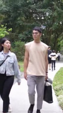 Tayvanlı genç bir çiftin yirmili yaşlarda Taipei 'nin Xinyi İlçesi sokaklarında yürürken çekilmiş dikey bir videosu. Adam kolsuz bir bluz giyiyor ve kadın kot ceket giyiyor..