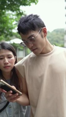 Tayvanlı genç bir çiftin yirmili yaşlarda Taipei 'nin Xinyi İlçesi sokaklarında yürürken çekilmiş dikey bir videosu. Adam kolsuz bir bluz giyiyor ve kadın kot ceket giyiyor..