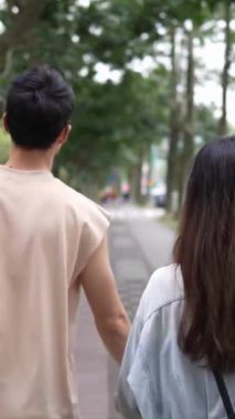 Tayvanlı genç bir çiftin yirmili yaşlarda Taipei 'nin Xinyi İlçesi sokaklarında yürürken çekilmiş dikey bir videosu. Adam kolsuz bir bluz giyiyor ve kadın kot ceket giyiyor..