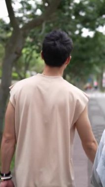 Tayvanlı genç bir çiftin yirmili yaşlarda Taipei 'nin Xinyi İlçesi sokaklarında yürürken çekilmiş dikey bir videosu. Adam kolsuz bir bluz giyiyor ve kadın kot ceket giyiyor..