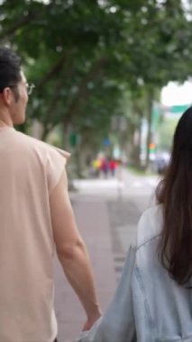 Tayvanlı genç bir çiftin yirmili yaşlarda Taipei 'nin Xinyi İlçesi sokaklarında yürürken çekilmiş dikey bir videosu. Adam kolsuz bir bluz giyiyor ve kadın kot ceket giyiyor..