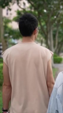 Tayvanlı genç bir çiftin yirmili yaşlarda Taipei 'nin Xinyi İlçesi sokaklarında yürürken çekilmiş dikey bir videosu. Adam kolsuz bir bluz giyiyor ve kadın kot ceket giyiyor..