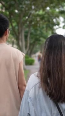 Tayvanlı genç bir çiftin yirmili yaşlarda Taipei 'nin Xinyi İlçesi sokaklarında yürürken çekilmiş dikey bir videosu. Adam kolsuz bir bluz giyiyor ve kadın kot ceket giyiyor..