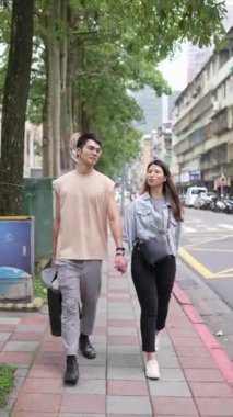 Tayvanlı genç bir çiftin yirmili yaşlarda Taipei 'nin Xinyi İlçesi sokaklarında yürürken çekilmiş dikey bir videosu. Adam kolsuz bir bluz giyiyor ve kadın kot ceket giyiyor..