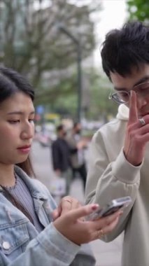 Taipei 'nin Xinyi İlçesi sokaklarında yirmili yaşlarında genç bir Tayvanlı kadının yanında kapüşonlu bir adam dururken çekilmiş dikey bir videosu..