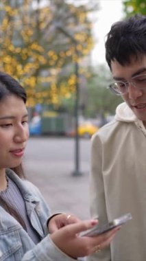 Taipei 'nin Xinyi İlçesi sokaklarında yirmili yaşlarında genç bir Tayvanlı kadının yanında kapüşonlu bir adam dururken çekilmiş dikey bir videosu..