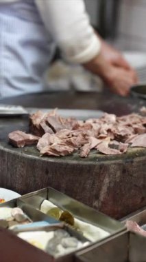 Taipei 'nin Wanhua semtindeki bir alışveriş caddesinde yerel bir restoranın mutfağında et doğrayan Tayvanlı bir kadının dikey yavaş çekim videosu..
