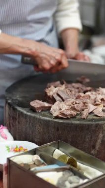 Taipei 'nin Wanhua semtindeki bir alışveriş caddesinde yerel bir restoranın mutfağında et doğrayan Tayvanlı bir kadının dikey yavaş çekim videosu..
