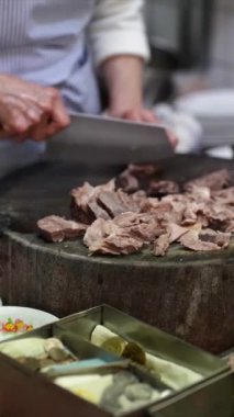 Taipei 'nin Wanhua semtindeki bir alışveriş caddesinde yerel bir restoranın mutfağında et doğrayan Tayvanlı bir kadının dikey yavaş çekim videosu..