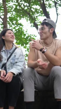 Tayvanlı genç bir çiftin Taipei 'deki Xinyi Bölgesi dağlarında oturup konuştuğu dikey ağır çekim bir video. Adam kolsuz bir bluz giyiyor.