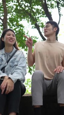 Tayvanlı genç bir çiftin Taipei 'deki Xinyi Bölgesi dağlarında oturup konuştuğu dikey ağır çekim bir video. Adam kolsuz bir bluz giyiyor.