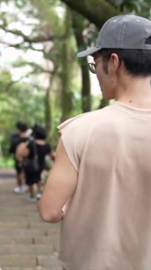 Taipei 'nin Xinyi İlçesi' nde küçük bir patika boyunca yürüyen ve konuşan 20 'li yaşlarda genç bir Tayvanlı çiftin dikey yavaş çekim videosu. Adam kolsuz bir bluz giyiyor.