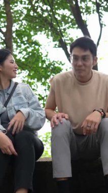 Tayvanlı genç bir çiftin Taipei 'deki Xinyi Bölgesi dağlarında oturup konuştuğu dikey ağır çekim bir video. Adam kolsuz bir bluz giyiyor.