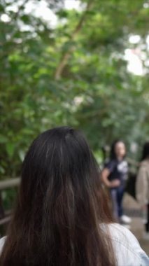 Taipei 'nin Xinyi İlçesi' nde küçük bir patika boyunca yürüyen ve konuşan 20 'li yaşlarda genç bir Tayvanlı çiftin dikey yavaş çekim videosu. Adam kolsuz bir bluz giyiyor.