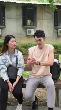 Tayvanlı genç bir çiftin yirmili yaşlarda bir bankta oturup Taipei 'nin Xinyi İlçesi' ndeki bir parkta konuştuğu dikey ağır çekim bir video..