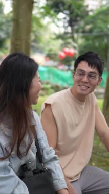 Tayvanlı genç bir çiftin yirmili yaşlarda bir bankta oturup Taipei 'nin Xinyi İlçesi' ndeki bir parkta konuştuğu dikey ağır çekim bir video..