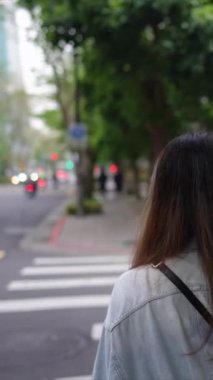 Taipei 'nin Xinyi İlçesi sokaklarında yirmili yaşlarda genç bir Tayvanlı çiftin bahar öğleden sonra yürüdüğü dikey ağır çekim bir video. Adam kapüşonlu giyiyor.