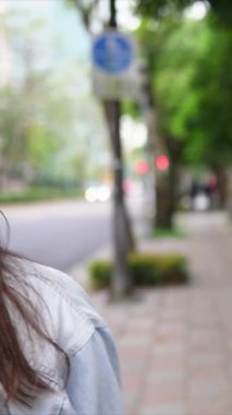 Taipei 'nin Xinyi İlçesi sokaklarında yirmili yaşlarda genç bir Tayvanlı çiftin bahar öğleden sonra yürüdüğü dikey ağır çekim bir video. Adam kapüşonlu giyiyor.