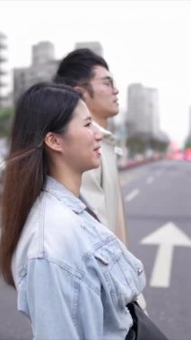 Taipei 'nin Xinyi İlçesi sokaklarında yirmili yaşlarda genç bir Tayvanlı çiftin bahar öğleden sonra yürüdüğü dikey ağır çekim bir video. Adam kapüşonlu giyiyor.