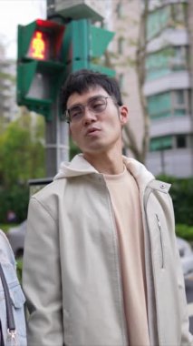Taipei 'nin Xinyi İlçesi sokaklarında yirmili yaşlarda genç bir Tayvanlı çiftin bahar öğleden sonra yürüdüğü dikey ağır çekim bir video. Adam kapüşonlu giyiyor.